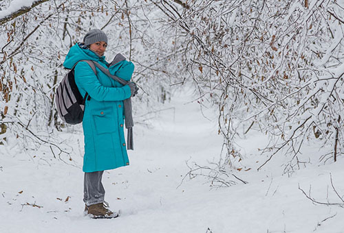 Женщина гуляет с новорожденным зимой
